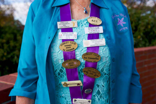 ACT Shirley Club acting coordinator Shirley Towner standing outdoors with Shirley name club badges adorning her.