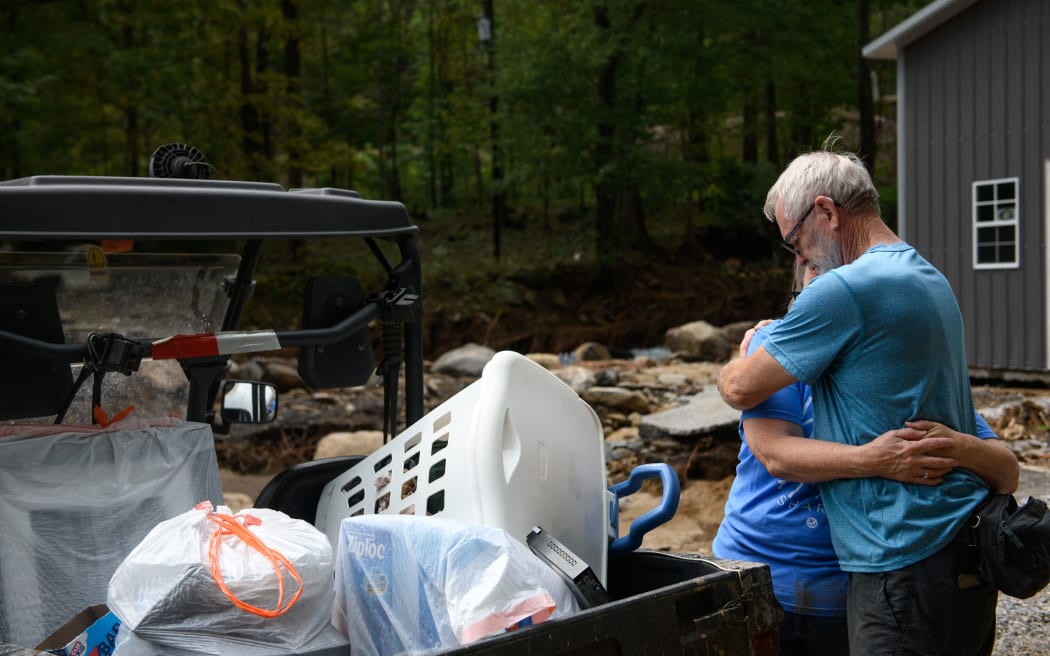 OLD FORT, NORTH CAROLINA - SEPTEMBER 30: Ron Grindstaff, right, comforts his wife, Marie, as they remove belongings from their home in the aftermath of Hurricane Helene on September 30, 2024 in Old Fort, North Carolina. According to reports, at least 100 people have been killed across the southeastern U.S., and millions are without power due to the storm, which made landfall as a Category 4 hurricane on Thursday. The White House has approved disaster declarations in North Carolina, Florida, South Carolina, Tennessee, Georgia, Virginia and Alabama, freeing up federal emergency management money and resources for those states.   Melissa Sue Gerrits/Getty Images/AFP (Photo by Melissa Sue Gerrits / GETTY IMAGES NORTH AMERICA / Getty Images via AFP)