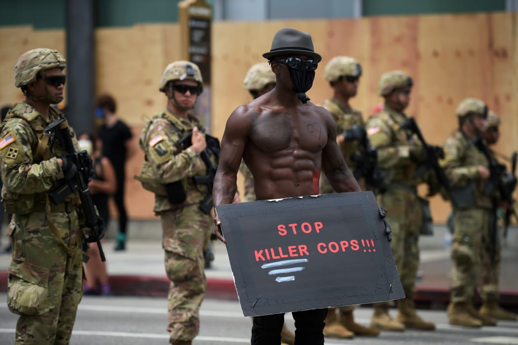A protester holds a placard in front of a row of Army National Guard during a demonstration over the death of George Floyd in Hollywood