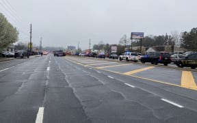 A line of law enforcement cars block the area of a shooting at a spa in an Atlanta suburb.