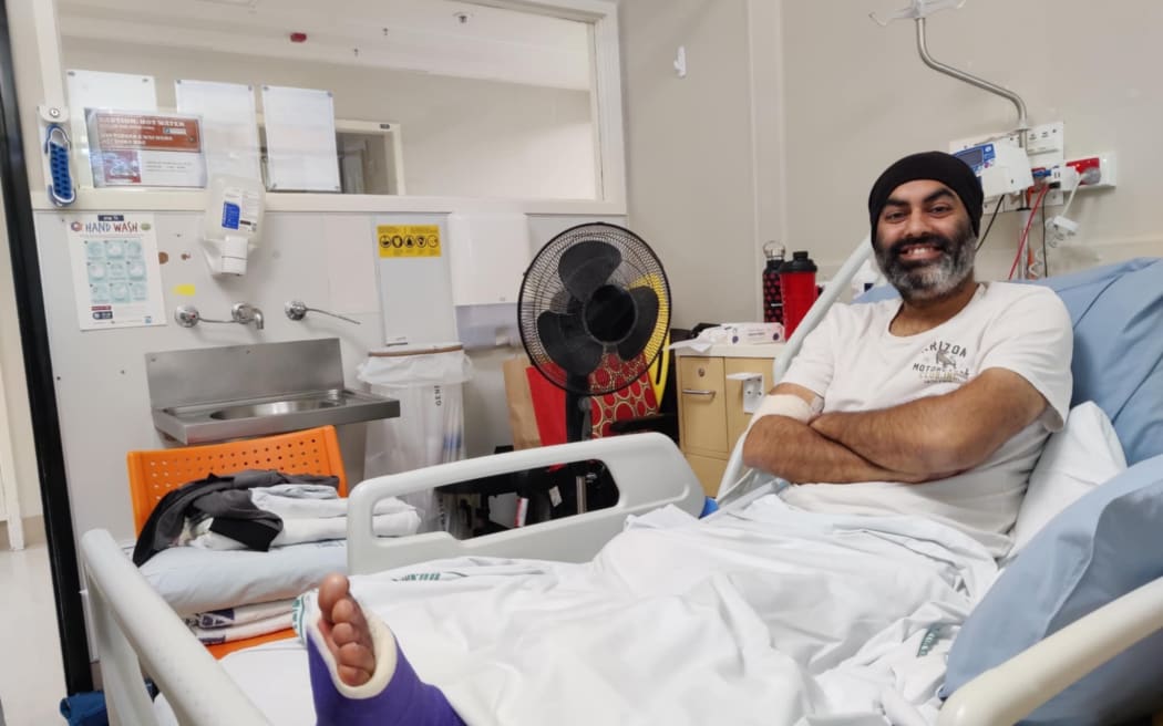 Pawanjit Singh Ghatora in hospital after having one of his legs amputated, the remaining leg is in a purple cast as the foot is fractured.