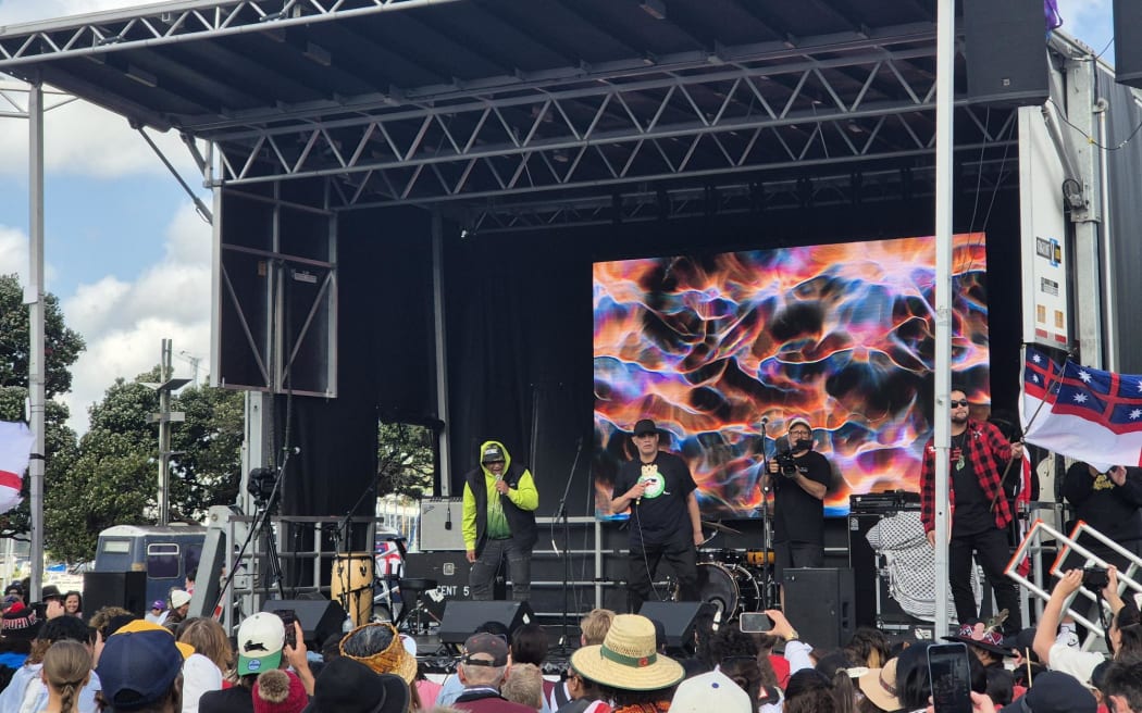 Local group 'Iwi' are delivering some serious hip hop beats from the stage at Waitangi Park. They say the key takeaway from this hīkoi is: "How the rangatahi are taking the lead and pushing us forward in these turbulent times".