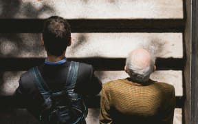 Two men, middle aged and elderly, walking side by side on stairs.