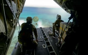Australian Army Cpl. Teome Matamua and Sgt. Phillip McIllvaney, 176th Air Dispatch Squadron loadmasters, deliver the first low-cost, low-altitude bundle of Operation Christmas Drop 2015 to the island of Mogmog, Dec. 8, 2015.