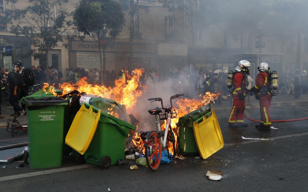 Firefighters look on as rubbish bins and other material burns during a climate change protest in Paris on September 21, 2019.