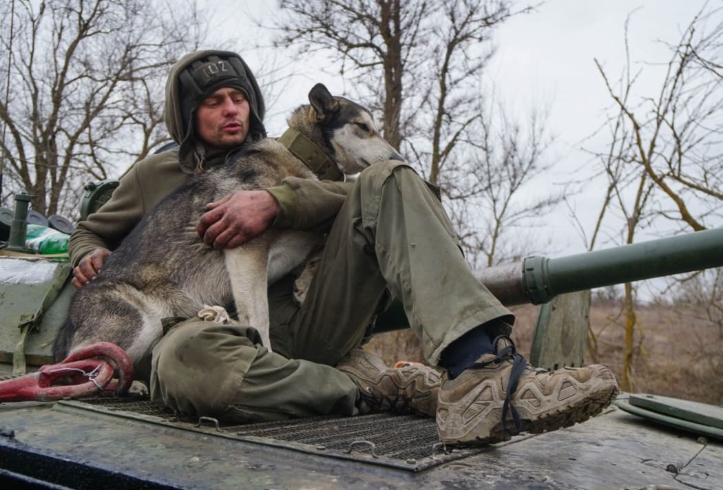A serviceman of militia of Donetsk People's Republic (DPR) with a dog sits on an armoured vehicle outside Mariupol, Ukraine.