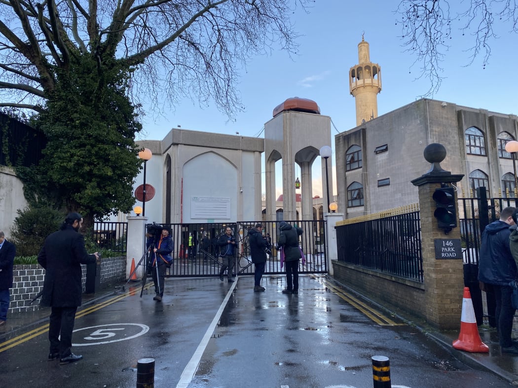 Press members are seen behind the entrance door as police officers take security measures after a knifeman stabbed a Muslim prayer leader in the neck while performing the call to prayer at London mosque in London.