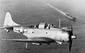 An SBD Dauntless flying over the USS Enterprise.