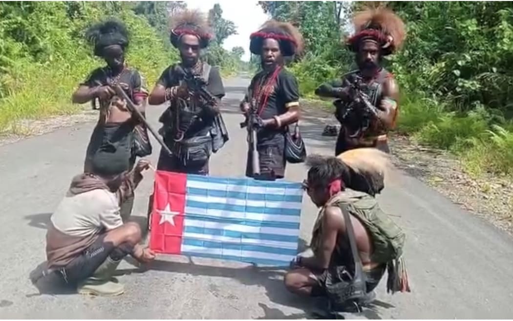 West Papuan freedom fighters pose with guns and the West Papuan nationalist flag after their attack on aircraft as part of an ongoing conflict with the Indonesian state.