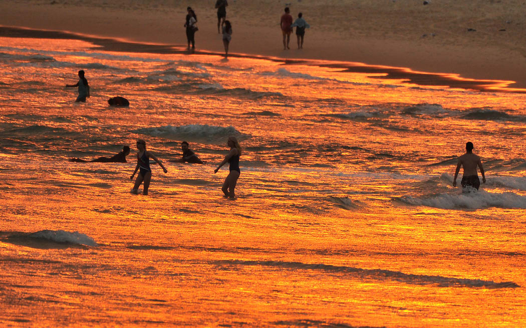 Beachgoers enjoy the sunset at Bondi beach during a heatwave in Sydney on December 19, 2019. A state of emergency was declared in Australia's most populated region on December 19 as an unprecedented heatwave fanned out-of-control bushfires, destroying homes and smothering huge areas with a toxic smoke. (Photo by FAROOQ KHAN / AFP)