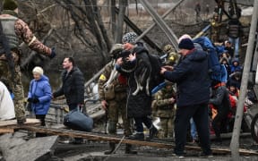 People cross a destroyed bridge as they  evacuate the city of Irpin, northwest of Kyiv, during heavy shelling and bombing on March 5, 2022, 10 days after Russia launched a military invasion of Ukraine.