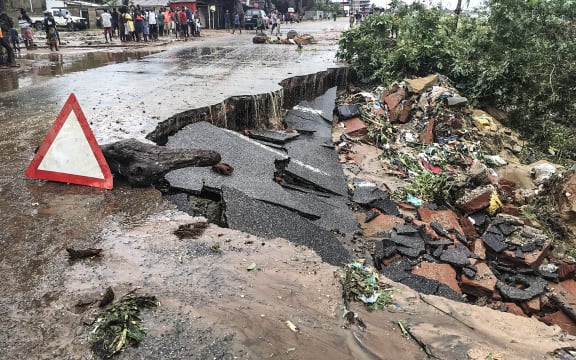Residents stand next to a road partially destroyed by Cyclone Kenneth.