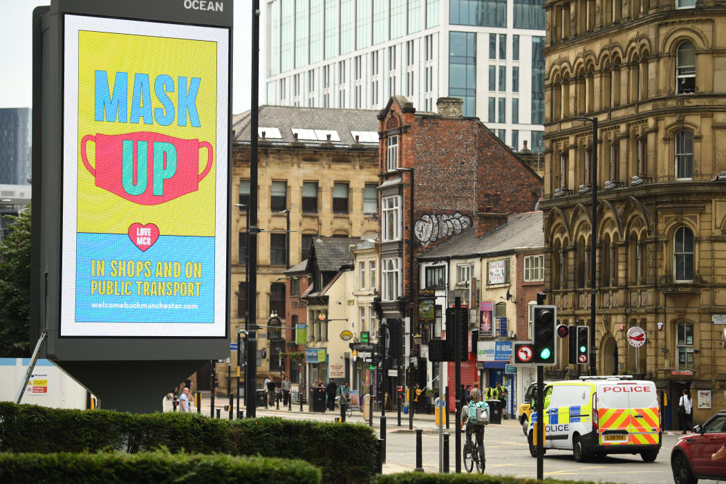 A large electronic billboard displays a message urging people to wear masks to reduce the spread of Covid-19.