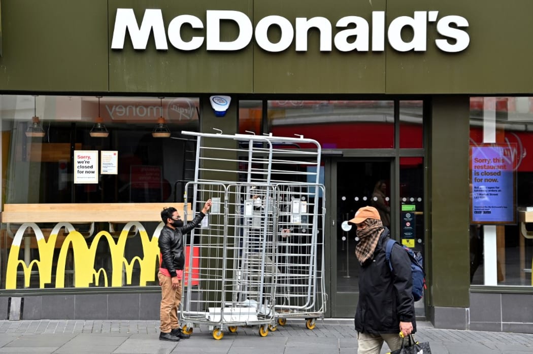 A worker wearing PPE (personal protective equipment), of a face mask or covering as a precautionary measure against spreading COVID-19, wheels barriers into a branch of McDonalds in the city centre of Leicester.