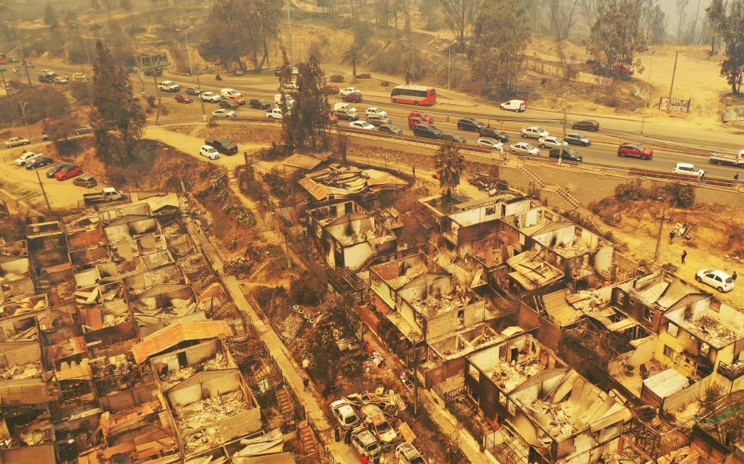 Aerial view of burned houses after a forest fire that affected the hills in Quilpe, Viña del Mar, Chile, taken on February 3, 2024. The region of Valparaiso and Viña del Mar, in central Chile, woke up on Saturday with a partial curfew to allow the movement of evacuees and the transfer of emergency equipment in the midst of a series of unprecedented fires, authorities reported. (Photo by RODRIGO ARANGUA / AFP)