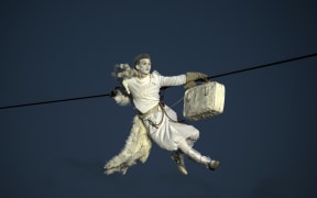 A performer is suspended from high-wires during the outdoor aerial performance of the show "Place des Anges" (Angels' square).