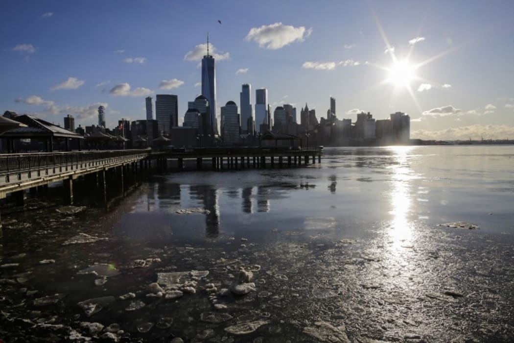 Ice floats along the Hudson River, with  the skyline of New York City and One world Trade Center.