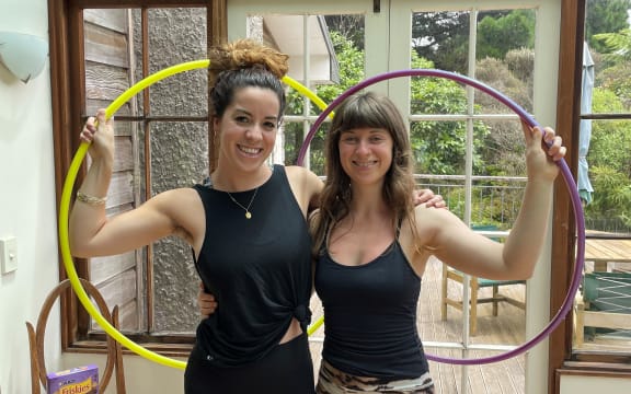 Two women holding hula hoops and smiling.