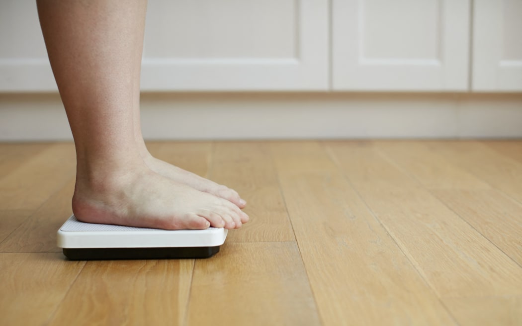 Woman standing on weighing scales. (Photo by Science Photo Library / R3F / Science Photo Library via AFP)