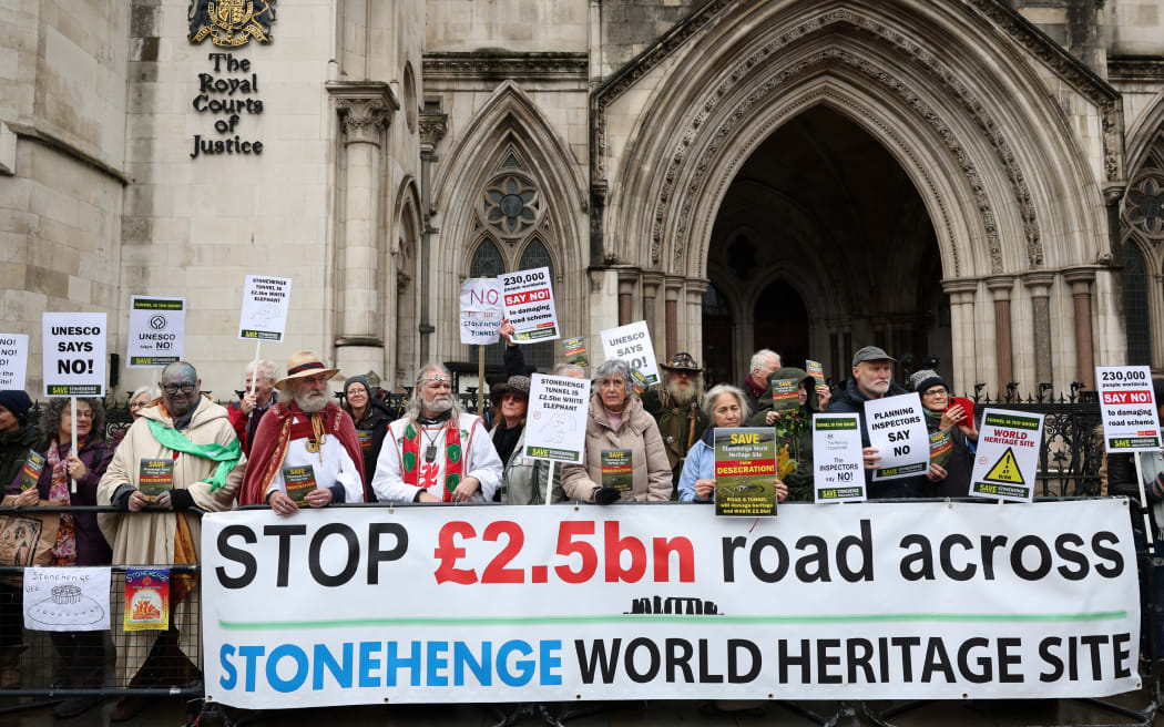 Demonstrators pose during a protest outside the Royal Courts of Justice, Britain's High Court, in central London on December 12, 2023, during a hearing  for Save Stonehenge World Heritage Site (SSWHS)'s legal challenge against a decision to approve a controversial road project, including a tunnel near Stonehenge. (Photo by Adrian DENNIS / AFP)