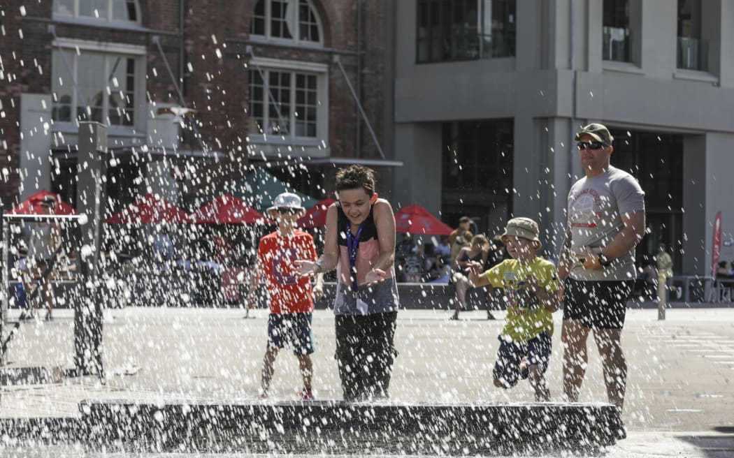 Summer in Wellington, a boy is splashed by the people jumping into the harbour.