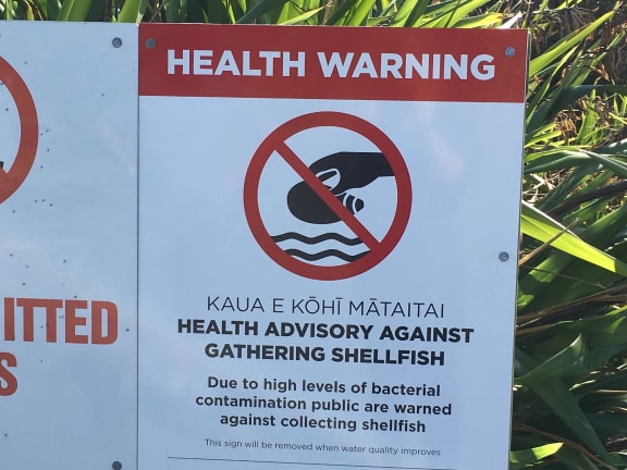 Health warning sign in front of the Waiotahe estuary pipi beds.
