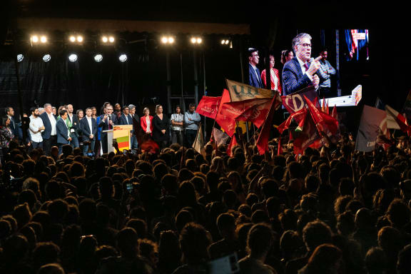 First Secretary of the French left-wing Socialist Party (PS) Olivier Faure addresses a speech on stage and is shown on screen (R) at a rally following the announcement of the results of the first round of French parliamentary elections, at Place de la Republique in Paris on June 30, 2024.