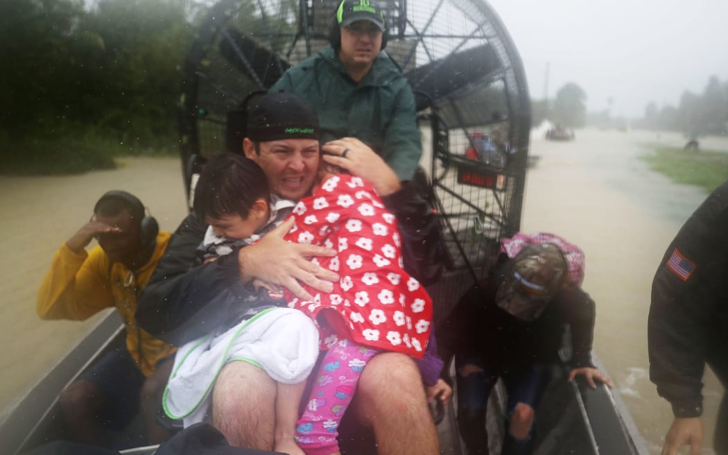 Dean Mize holds children as he and Jason Legnon use an airboat to rescue people from homes that are inundated with flooding from Hurricane Harvey.