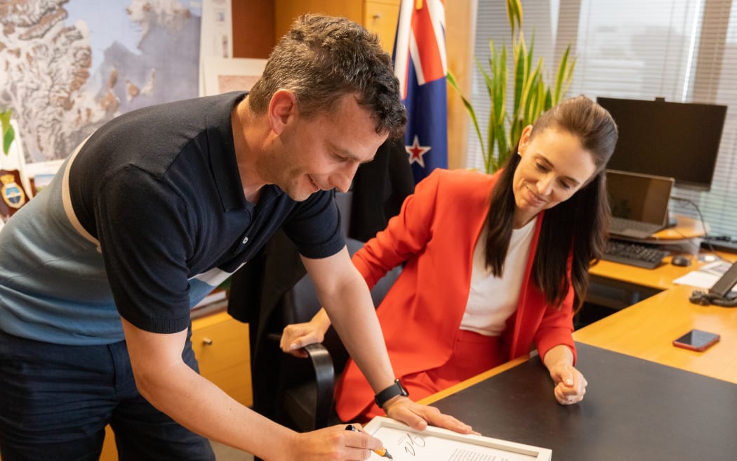 David Seymour and Jacinda Ardern with the signed transcript of her calling him an "arrogant prick" in Parliament. They plan to auction it off to charity.