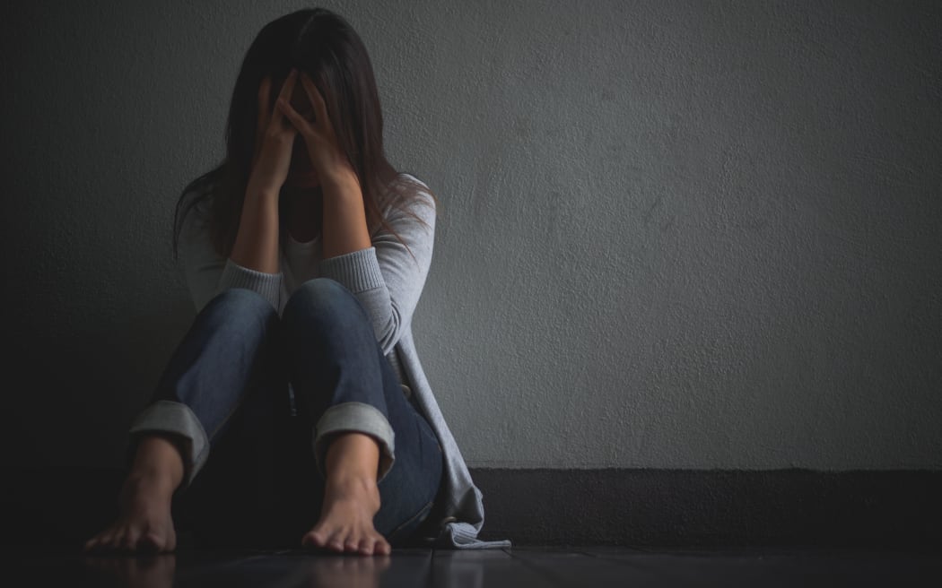 sad woman hug her knee and cry. Sad woman sitting alone in a empty room.