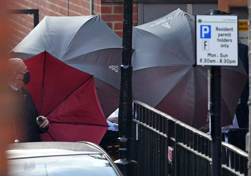 Staff use umbrellas to shield an individual wheeled to an ambulance parked outside King Edward VII's Hospital in central London on 1 March  2021