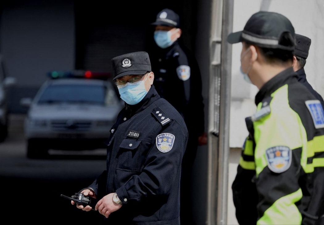 A policeman looks on as police vehicles exit the Dandong Intermediate People's Court, where the trial of Canadian businessman Michael Spavor under spying charges was held, in Dandong in China's northeast Liaoning province on March 19, 2021.
