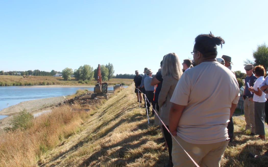 People watch as a stopbank is strengthened in Mataura, Southland.