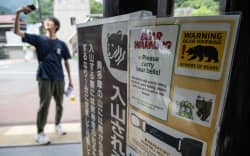 A man takes a picture at the train station near bear warning signs in Okutama on the outskirts of Tokyo on June 14, 2026, as local authorities urge visitors to take precautions following increased reports of bear sightings in the region. (Photo by Andrew CABALLERO-REYNOLDS / AFP)