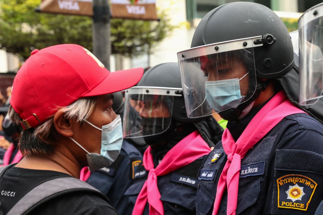 A pro-democracy protester faces off against a police officer in Bangkok on 15 October  2020, after the Thai government banned demonstrations.