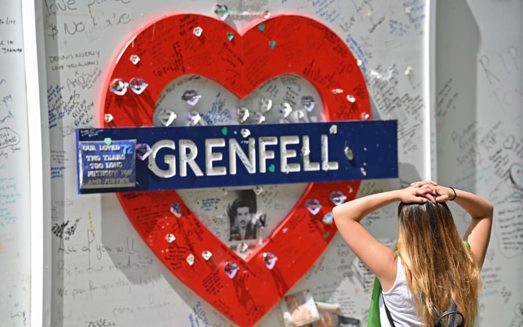A woman reads messages of support written on the wall surrounding Grenfell Tower in west London on June 14, 2020, on the third anniversary of the high-rise fire that killed 72 people.
