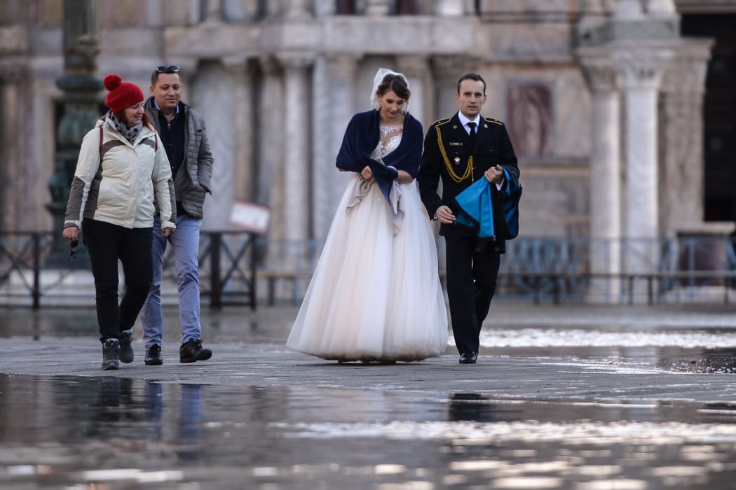 A newlywed couple walks across a flooded square on 14 November, 2019 in Venice.