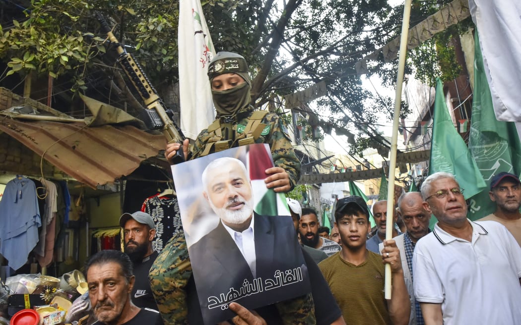 Demonstrators wave flags and hold pictures of the leader of the Palestinian militant Hamas group, Ismail Haniyeh, (C) and senior leader Saleh al-Arouri during a protest on July 31, 2024 in Beirut's Burj al-Barajneh camp for Palestinian refugees, denouncing his killing. Hamas said on July 31 its political leader Ismail Haniyeh was killed in an Israeli strike in Iran, where he was attending the swearing-in of the new president, and vowed the act "will not go unanswered". (Photo by Fadel ITANI / AFP)