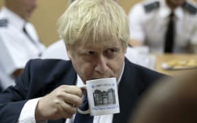Britain's Prime Minister Boris Johnson drinks from a HMP Leeds prison mug as he talks with prison staff during a visit to HM Prison Leeds, a Category B men's prison in Leeds, northern England, on August 13, 2019. (Photo by Jon Super / POOL / AFP)