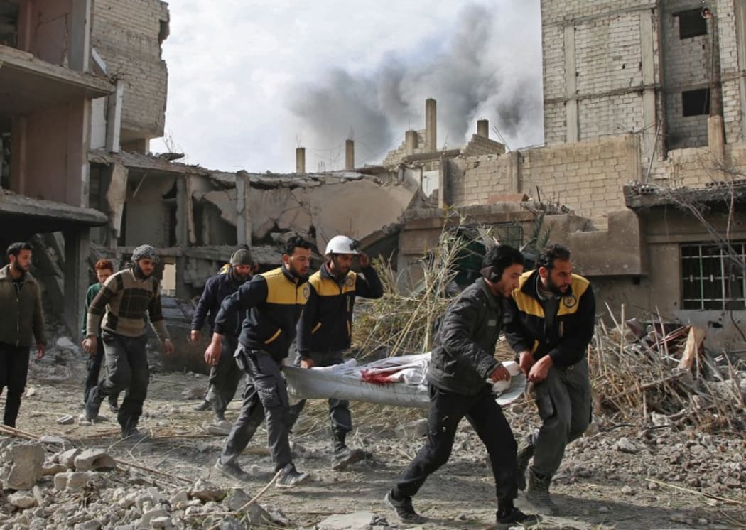 Members of Syrian civil defence forces known as White Helmets evacuate a victim of an air strike in the rebel-held enclave of Hazeh.