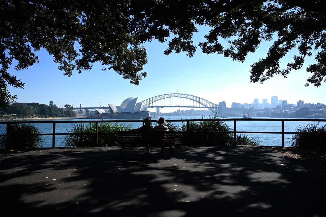 A couple enjoy the view of Sydney Harbour from Mrs Macquarie's Chair on May 3, 2021, as Australia's largest city is enveloped in a thick bank of hazardous bushfire smoke forcing authorities to scale back controlled forest burning nearby.