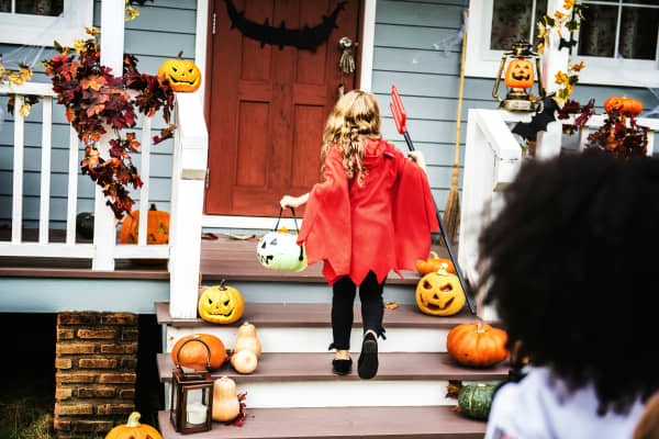 Child in red costume on door step, trick or treating for halloween.