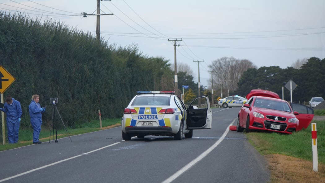Police investigators at Kuranui Road today and the two cars involved in the incident.