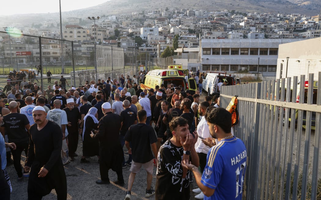 Israeli emergency services and local residents gather near a soccer field where a rocket hit in Majdal Shams.