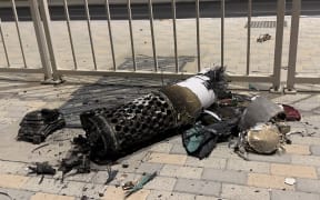 This frame grab taken from AFPTV footage shows the remnants of an Iranian missile intercepted over Qatar, as it lies on a pavement near a fence on June 23, 2025. Qatar said on June 23, the security situation was "stable" following an Iranian missile attack that targeted a US base on its territory in retaliation for American attacks on Iran nuclear sites.