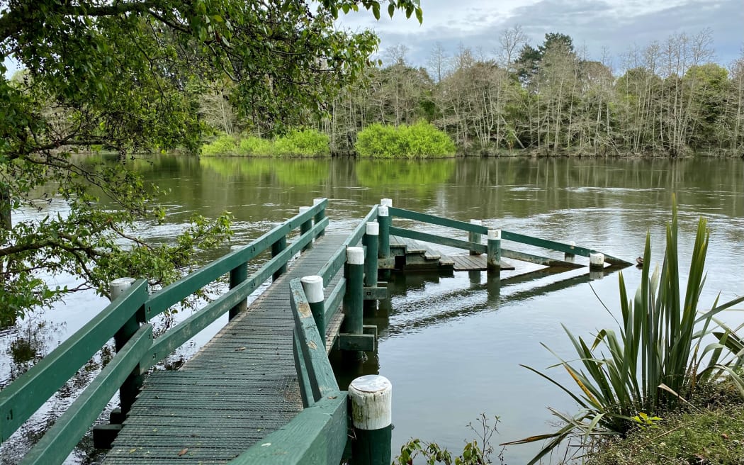 Waikato River water levels high, almost reaching the top step of a jetty.