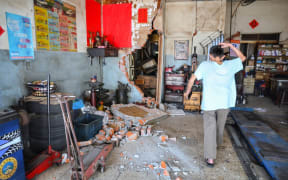 This photo taken by Taiwan's Central News Agency (CNA) on April 3, 2024 shows a man reacting after a brick wall in a house collapsed in Taipei, after a major earthquake hit Taiwan's east. A major 7.4-magnitude earthquake hit Taiwan's east on the morning of April 3, prompting tsunami warnings for the self-ruled island as well as parts of southern Japan and the Philippines. (Photo by CNA / AFP) / China OUT - Macau OUT - Taiwan OUT / HONG KONG OUT - RESTRICTED TO EDITORIAL USE