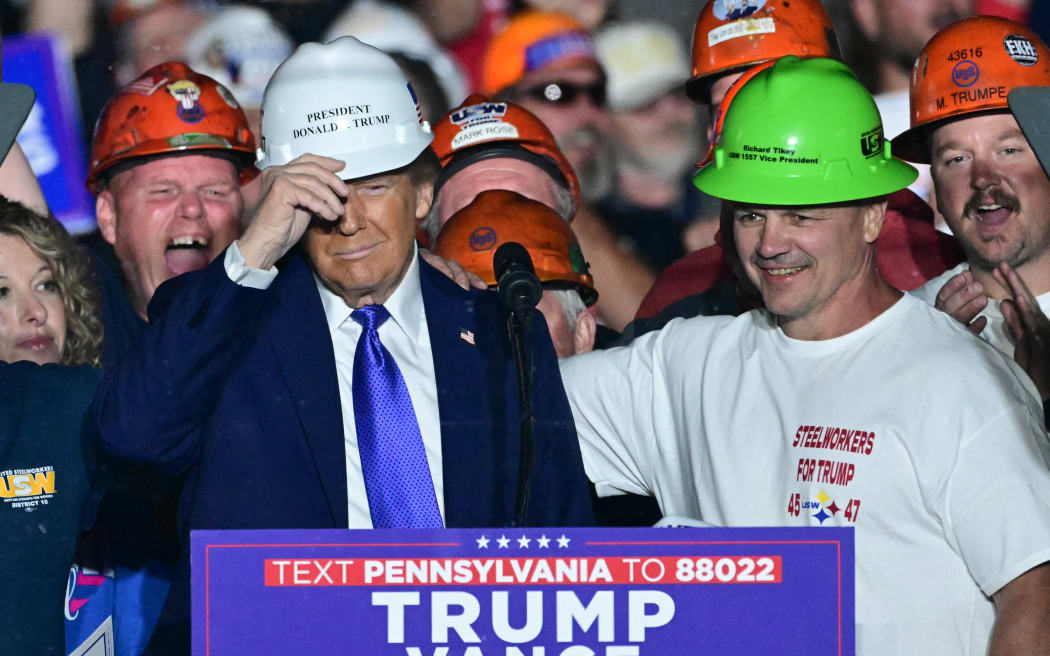 Members of "Steelworkers for Trump" gift former US President and Republican presidential candidate Donald Trump a hard hat during a campaign rally at Arnold Palmer Regional Airport in Latrobe, Pennsylvania, October 19, 2024. (Photo by Jim WATSON / AFP)