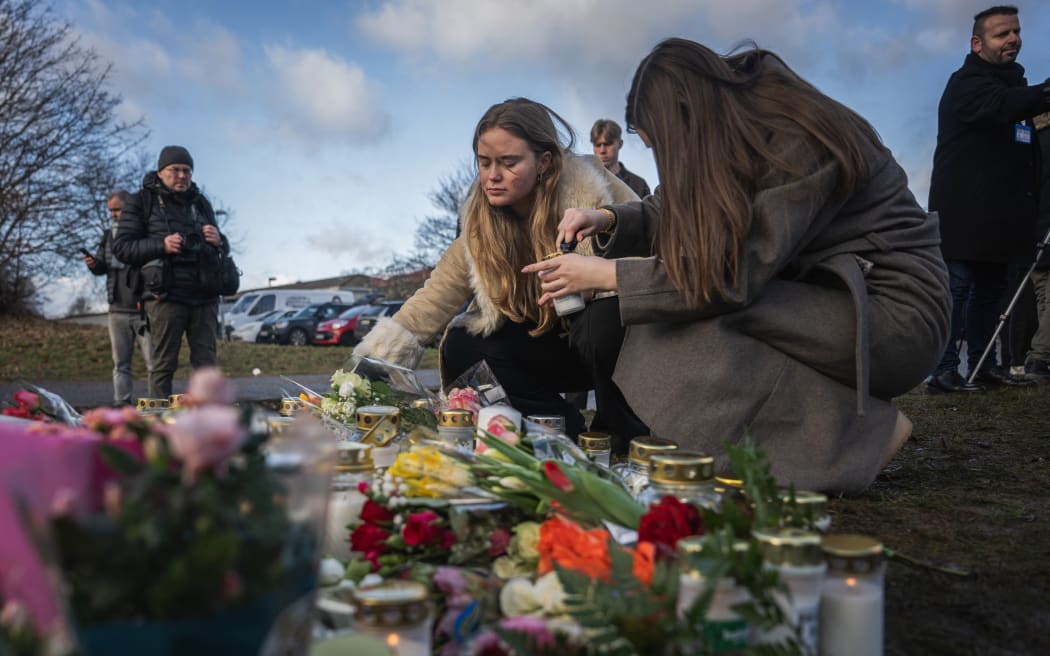 People light candles at a makeshift vigil near the adult education center Campus Risbergska school in Orebro, Sweden, on February 5, 2025 one day after a shooting there left eleven people dead. Eleven people have been killed in a shooting at an education centre in central Sweden on February 4, 2025, including the suspected assailant who was not known to police, police officials said. (Photo by Jonathan NACKSTRAND / AFP)