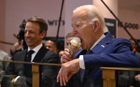 US President Joe Biden (R), flanked by host Seth Meyers (L), eats an ice cream cone at Van Leeuwen Ice Cream after taping an episode of "Late Night with Seth Meyers" in New York City on February 26, 2024. (Photo by Jim WATSON / AFP)